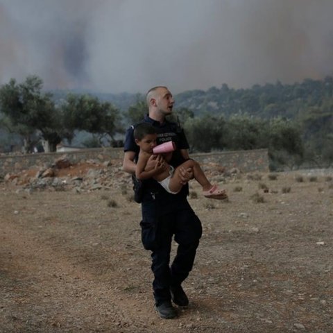 Πρωτοσέλιδο στα διεθνή Μέσα η φωτογραφία με τον αστυνομικό που πήρε αγκαλιά παιδί για να το σώσει